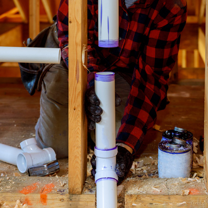 A plumber gluing together two pieces of pvc pipe. 