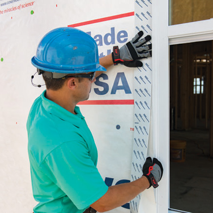 A construction worker waterproofing around the window at a worksite. 