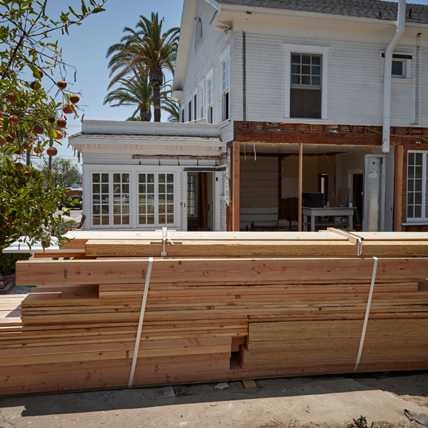 A large house getting a remodel with a stack of Ganahl lumber outside of the jobsite. 