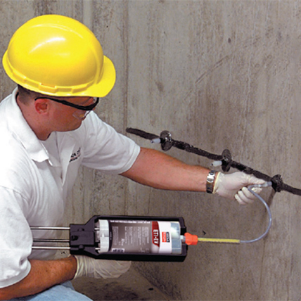 Construction worker applying epoxy to a wall. 