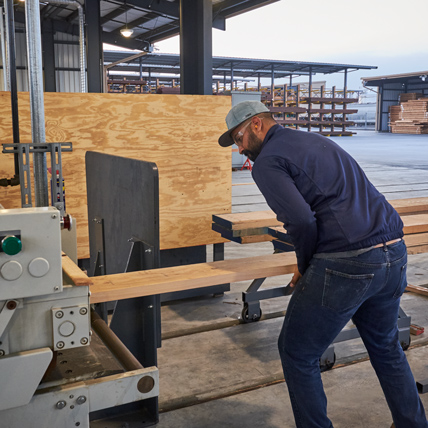 A Ganahl lumber employee using a machine to cut pieces of hardwood lumber. 