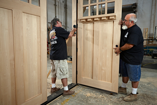 Two Ganahl employees working on a custom door in the mill shop. 