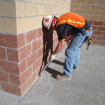 Construction worker caulking a brick wall. 